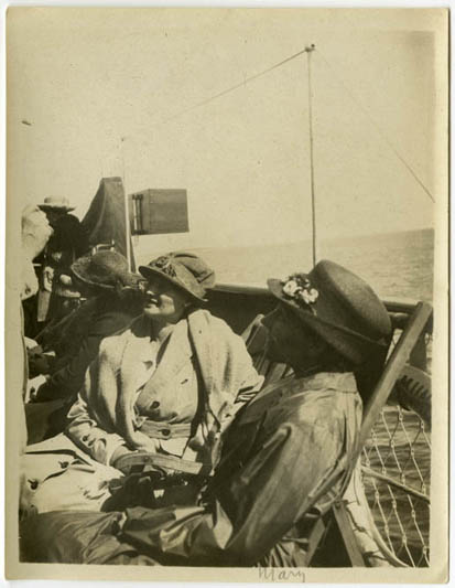 Neljä naista veneessä aurinkohatut päässä.